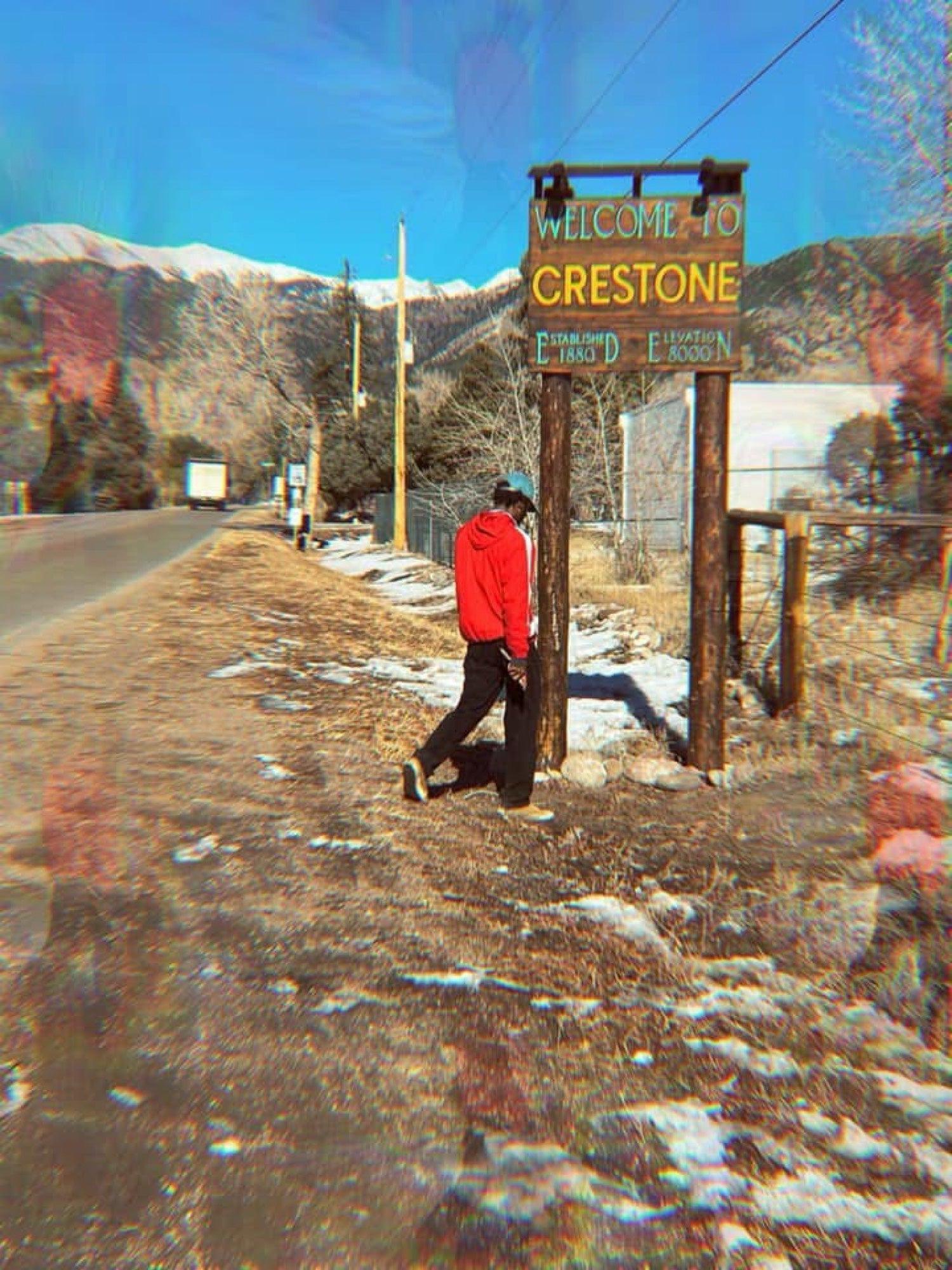 Kydale Outley walking past the Crestone sign, mountains behind him.