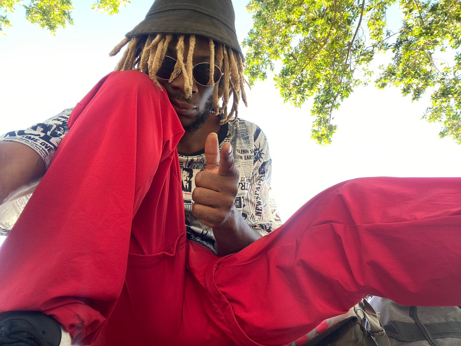 Kydale Outley in red, a bucket hat, trees overhead.